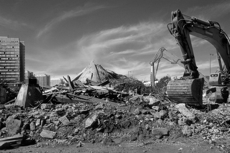 Zwei Bagger auf dem Ruinenfeld des weitgehend abgerissenen Gebäudes. Links im Hintergrund eines der Punkthochhäuser auf der Fischerinsel.